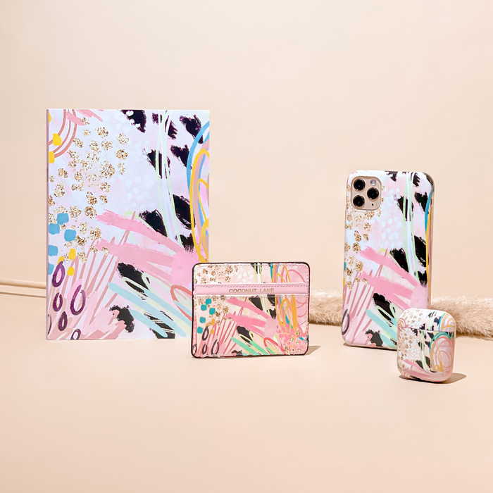 Coconut Lane card holder, notebook, phone case, and AirPods case with abstract patterns on a beige surface.
