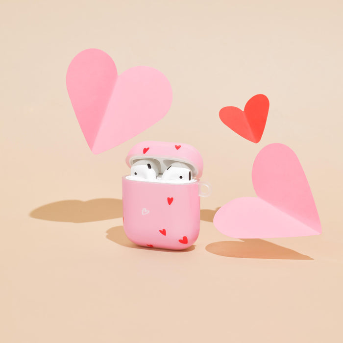 Beige Airpods case with a playful pink and red heart pattern from Coconut Lane.