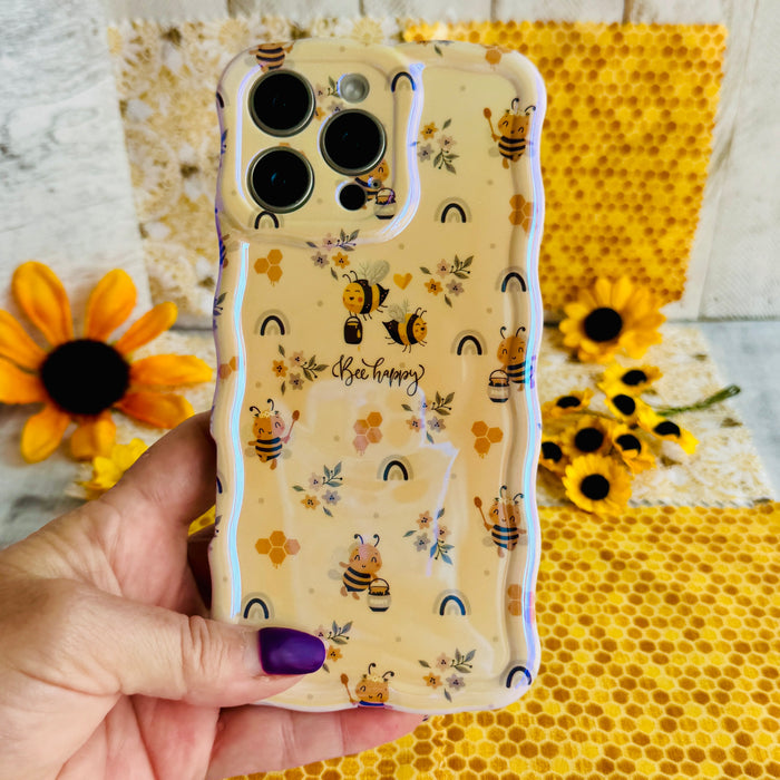 A phone case with a wavy edge design featuring floral prints and bees, held in a person's hand.