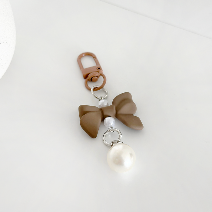 Brown Coquette Bow keyring with white beads and faux pearl, displayed on a white surface.