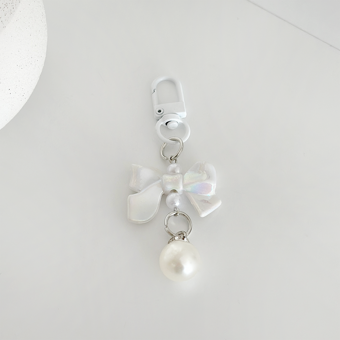 White iridescent bow keyring with a pearl charm, shown on a plain white background.