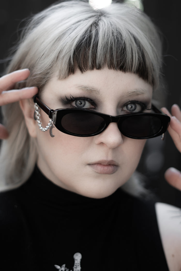 Model wearing False Idol Sunglasses by The Pretty Cult, black tinted rectangular shades