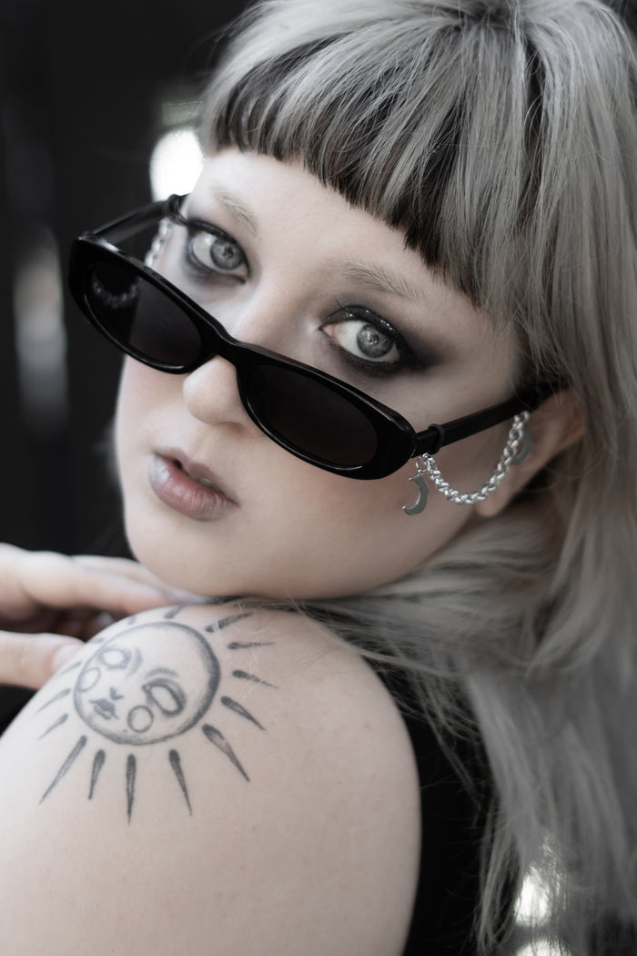 Close-up of False Idol Sunglasses showing dark tinted lenses and black frame