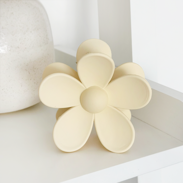 Cream-colored flower claw clip next to a round ceramic vase.