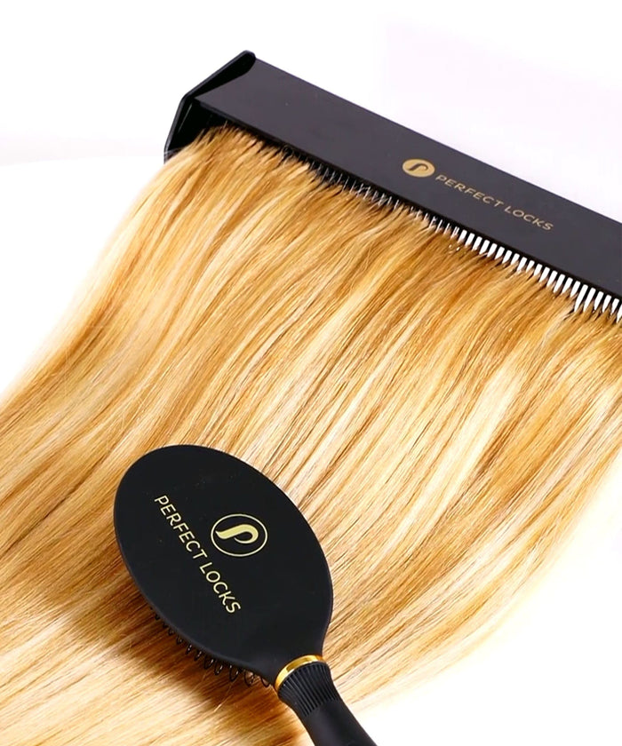 The black Perfect Locks Hair Extension Detangling Caddy is used to brush straight, blonde Remy hair extensions on a white background.#color_black