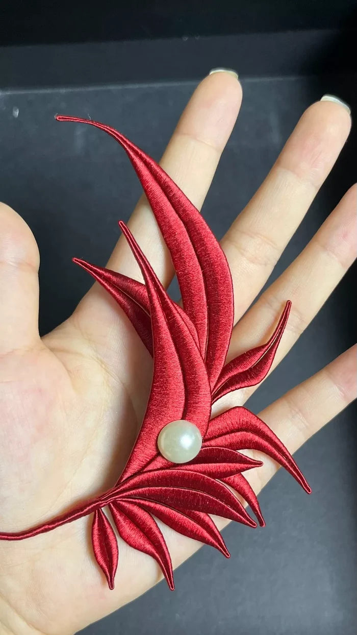 A red handmade Chanhua - style Zhang He hair accessory with a pearl in the center on a wooden box-5
