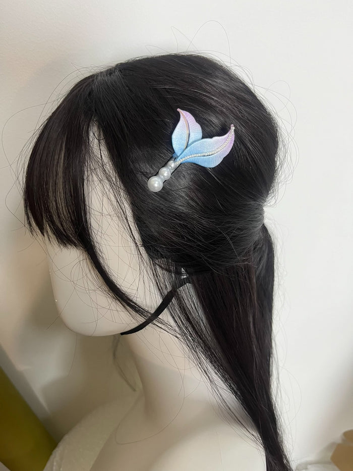 A handmade Chanhua mermaid - tail hair clip with blue and purple hues and pearl accents on black hair