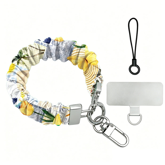 La Dolce Summer scrunchie phone wrist strap on a white background, showing the lemon and blue gingham Amalfi print fabric, silver lobster clasp, black loop cord, and clear attachment tab.