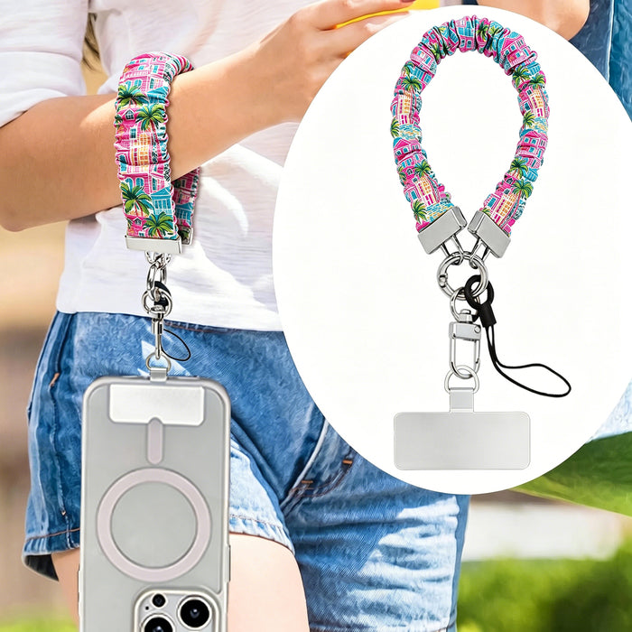 A vibrant La Palma Villa phone scrunchie wrist strap attached to a matching Wavy Luxe phone case with a colorful pink, green, and blue tropical palm tree print.