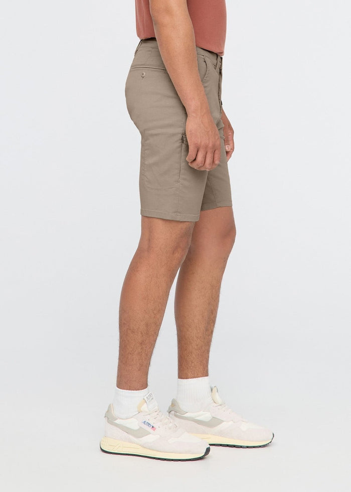 Sandstone shorts on model wearing rust-colored shirt and white sneakers, shown from side angle.