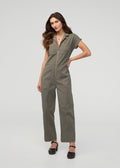 Thyme-colored boiler suit with short sleeves, front zip closure, and chest pockets worn with black platform sandals.