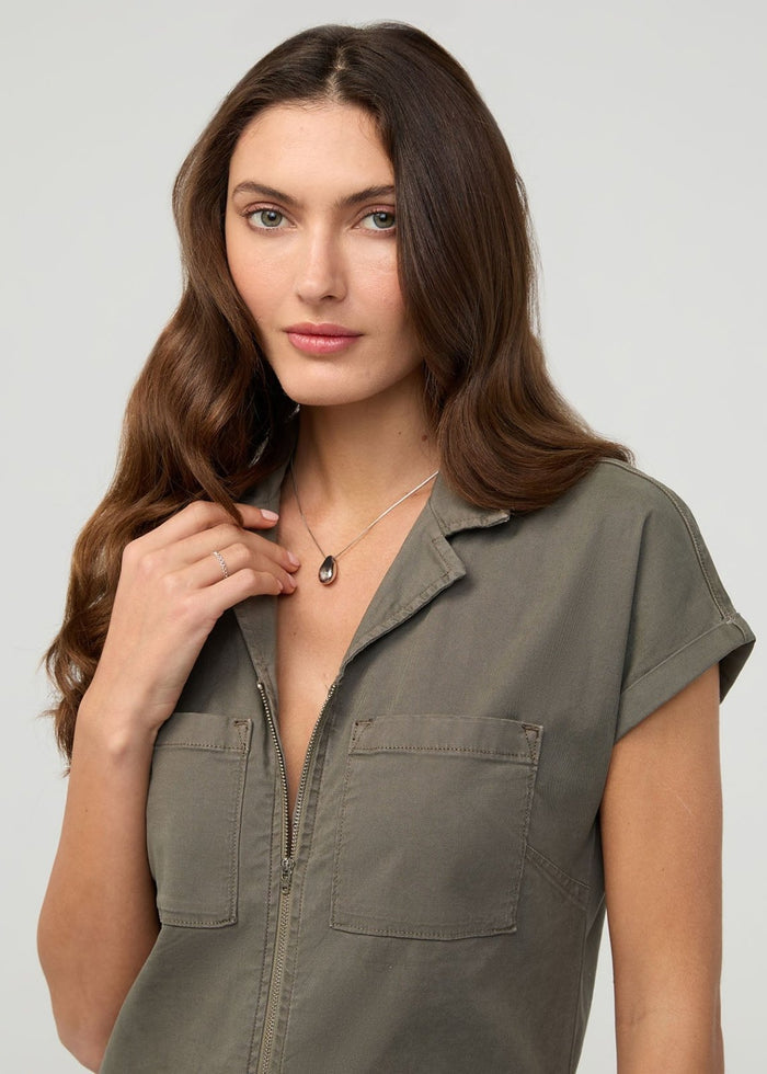 Woman wearing thyme-colored short-sleeve boiler suit with front zip closure and chest pockets.