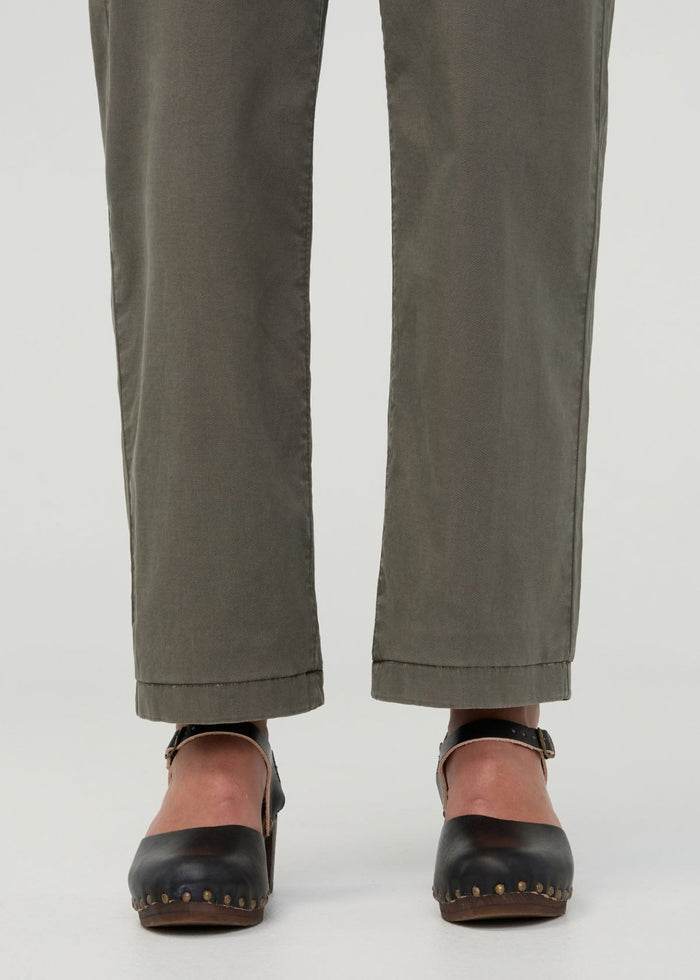 Thyme-colored boiler suit pants with cuffed hems, shown on model wearing black studded clogs.