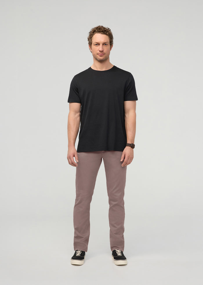 Man wearing black short-sleeve t-shirt and hazy mauve slim straight chino pants with black sneakers.