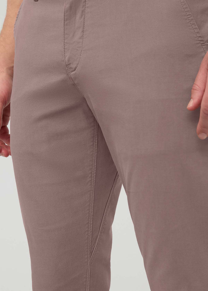 Hazy mauve slim straight chino pants with flat front seams and visible inseam detail on wearer.