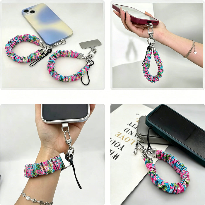 A vibrant Love Riot scrunchie phone wrist strap featuring a colorful neon graffiti "LOVE" and heart design attached to a matching Wavy Luxe phone case on a bright street art background.
