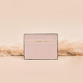 Pale pink vegan leather card holder with gold lettering and subtle soft detailing.