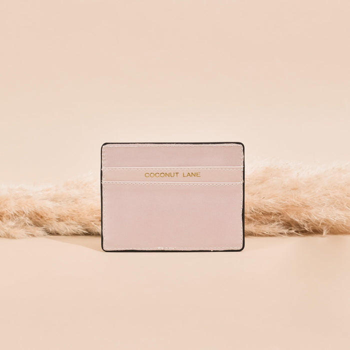 Pale pink vegan leather card holder with gold lettering and subtle soft detailing.
