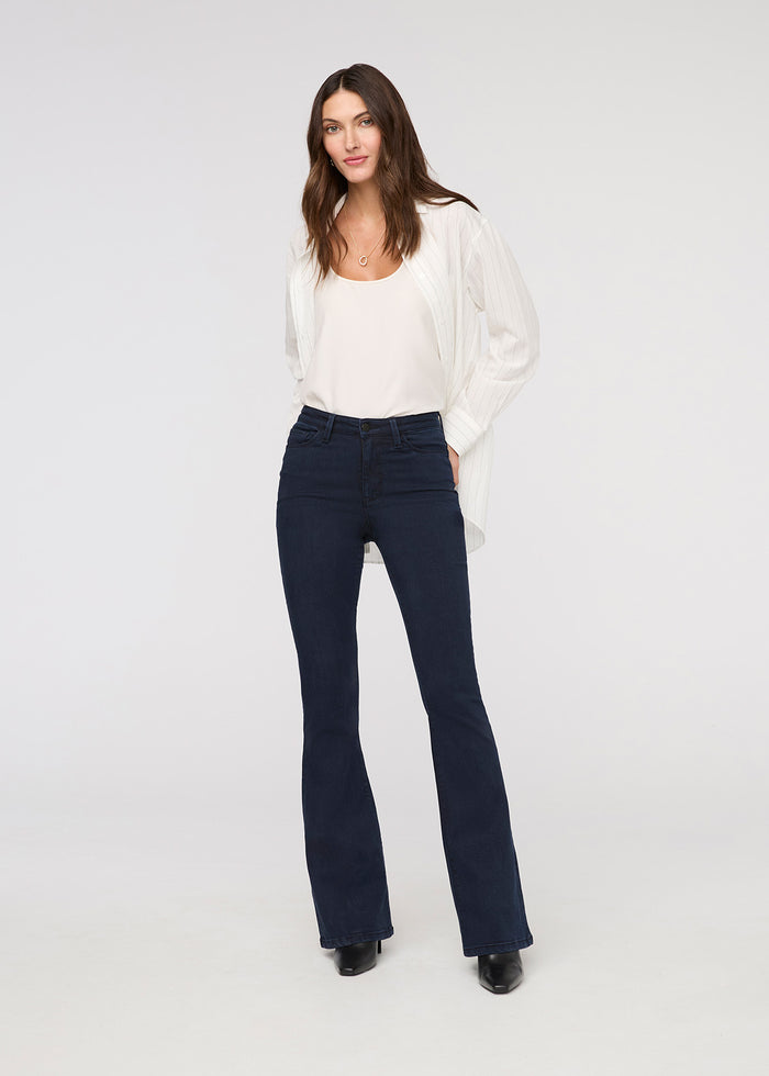 Woman wearing a white blouse and dark blue jeans on a white background