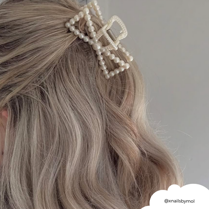 Wavy blonde hair held by a Coconut Lane pearl bow claw clip with a glossy finish.