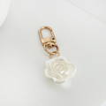 Gold keyring with a clasp and a white pearl flower charm.