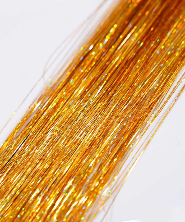 Close-up of fine, shiny ruby red strands of Perfect Hair Tinsel aligned to create a sparkling hair extension effect on light background.#color_bronze