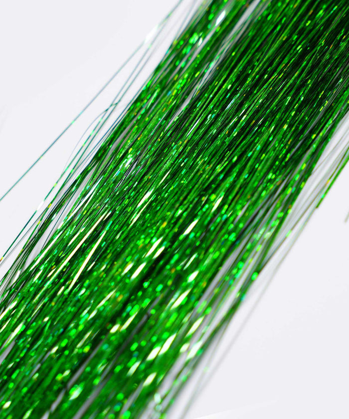 Close-up of Perfect Locks' Perfect Hair Tinsel in Shiny Silver, metallic strands overlap on a light background and sparkle.#color_emerald
