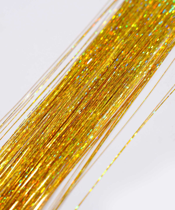 Close-up of many thin, shiny Royal Blue Perfect Hair Tinsel strands arranged in parallel on a light background, sparkling festively.#color_gold