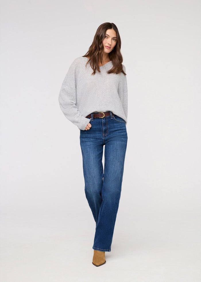 Woman wearing a gray sweater and blue jeans on a white background