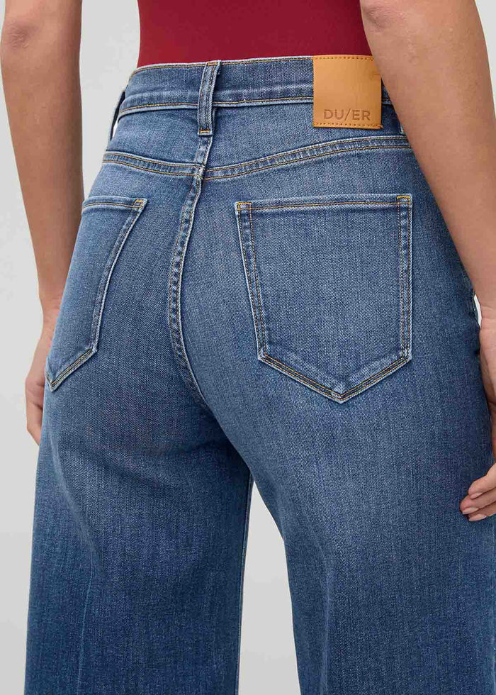 High rise wide leg crop denim in medium blue wash with tan leather label at waistband, shown from back.