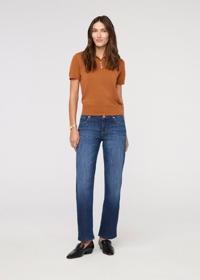 Woman wearing a brown polo shirt and blue jeans on a white background