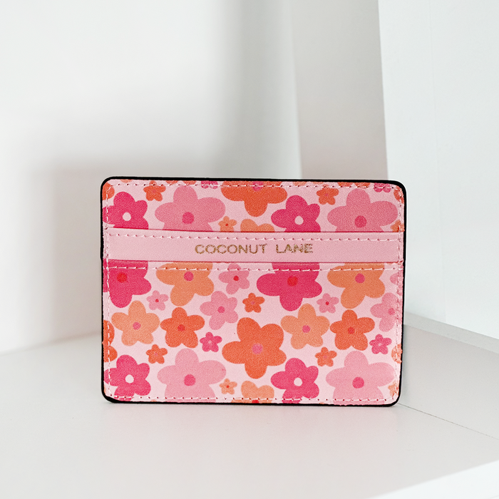 Pink and orange card holder with floral pattern, vegan leather texture, and embossed Coconut Lane branding on the front.