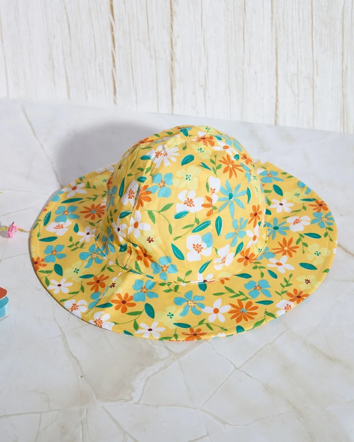 Wide-brim floral sun hat on yellow fabric with colorful flowers