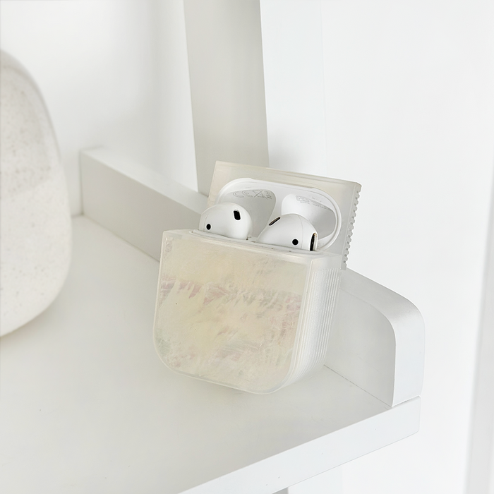 White natural shell AirPods case by Coconut Lane holding earbuds on a simple white shelf.