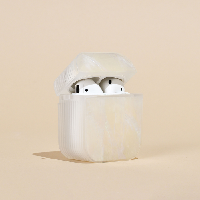 White wireless earbuds in a white Coconut Lane natural shell AirPods case with lid open, on a beige background.