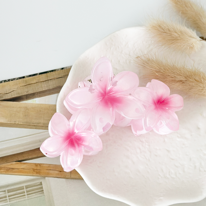Pink triple flower claw clip by Coconut Lane on a white plate with dried grass, shown in front of a mirror.
