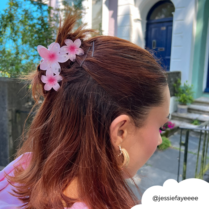 Pink Coconut Lane Triple Flower Claw Clip in brunette hair, worn outdoors with gold hoop earrings.